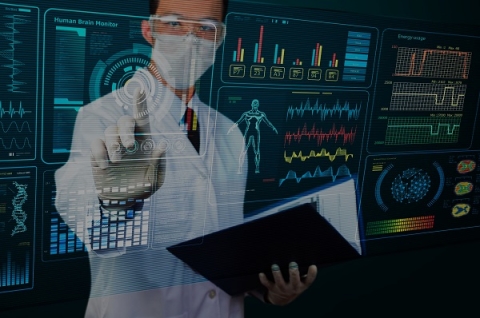 A masked medical doctor holding a notebook views displays of medical data